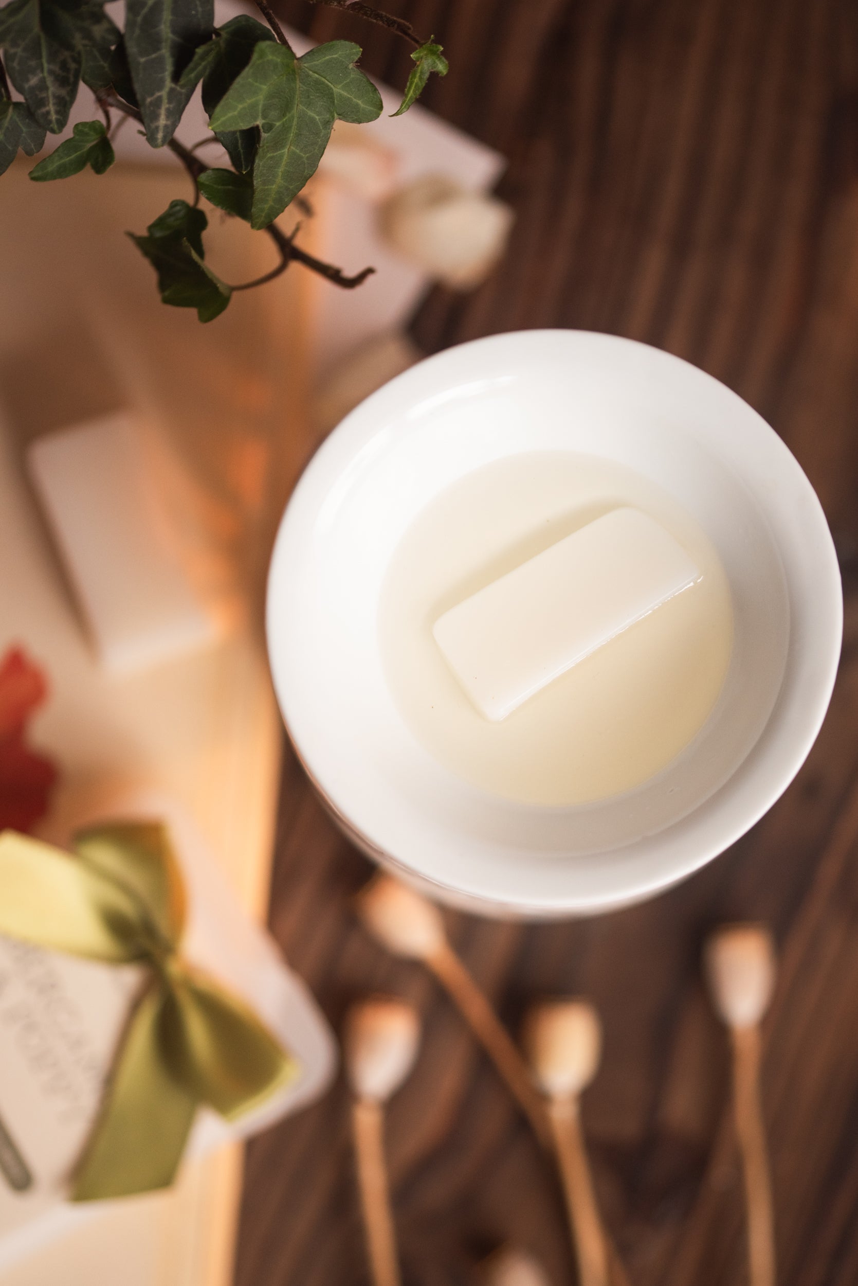 White wax melt in a white wax burner on a wooden surface with decorative items.