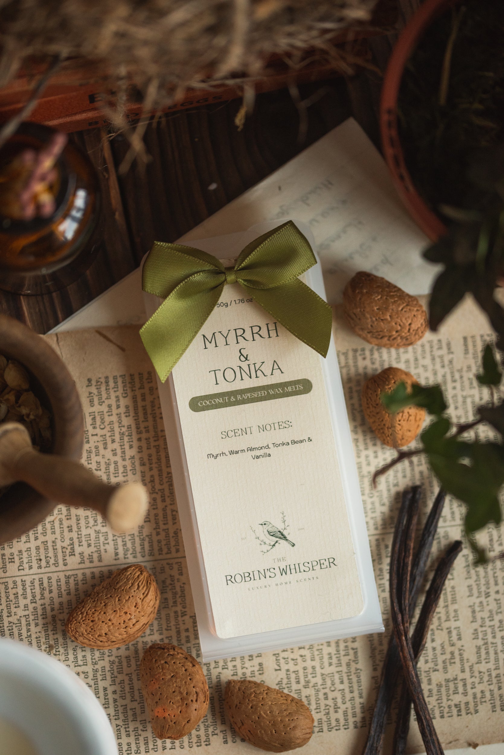 Myrrh & Tonka wax melt packaging with almonds and vanilla beans on a textured surface