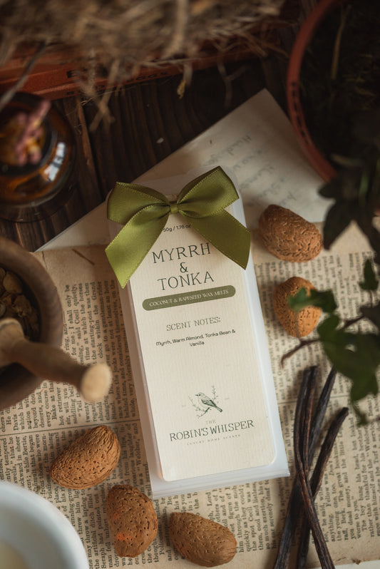 Myrrh & Tonka wax melt packaging with almonds and vanilla beans on a textured surface